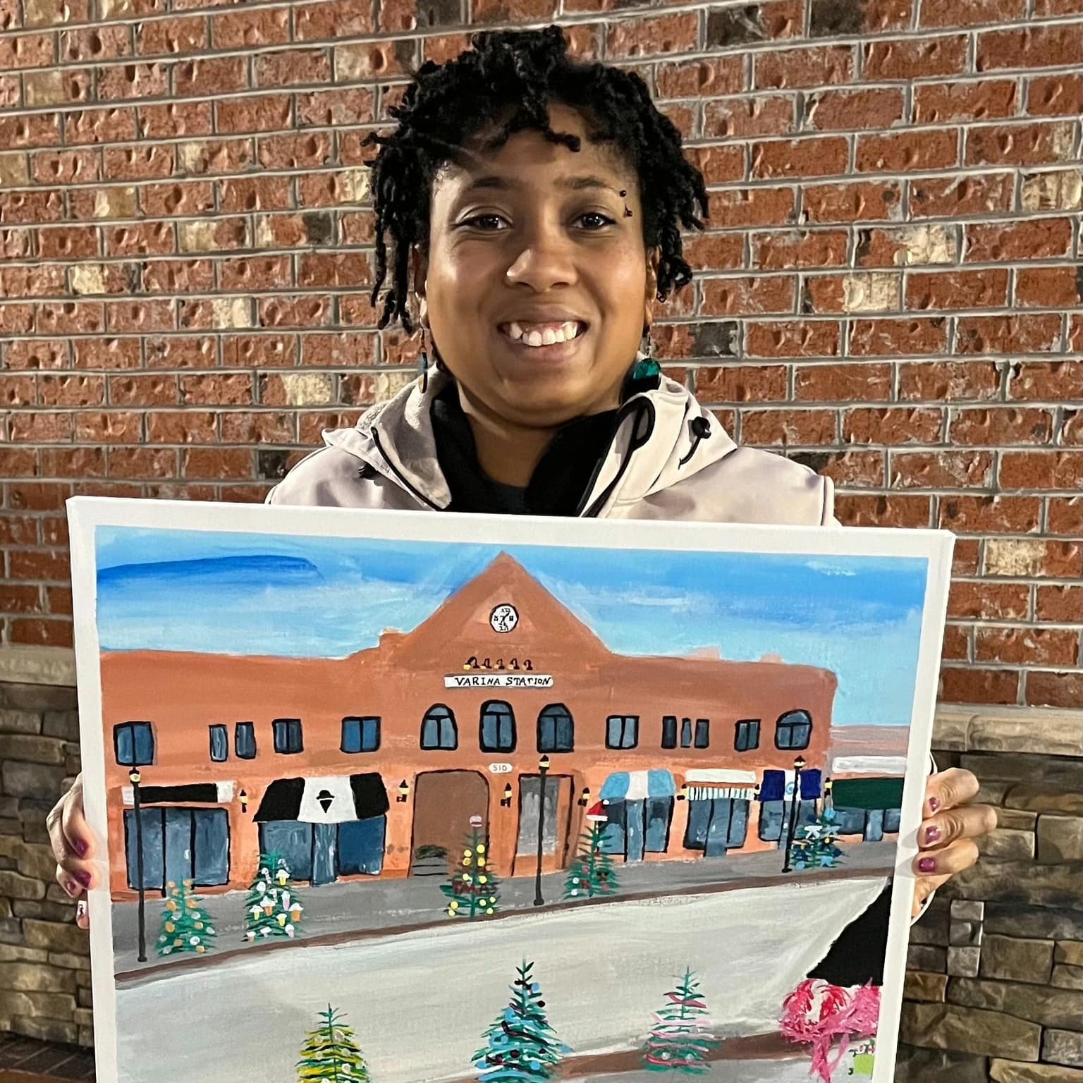 Jewell Shaw holding her painting of the Varina Station storefront building
