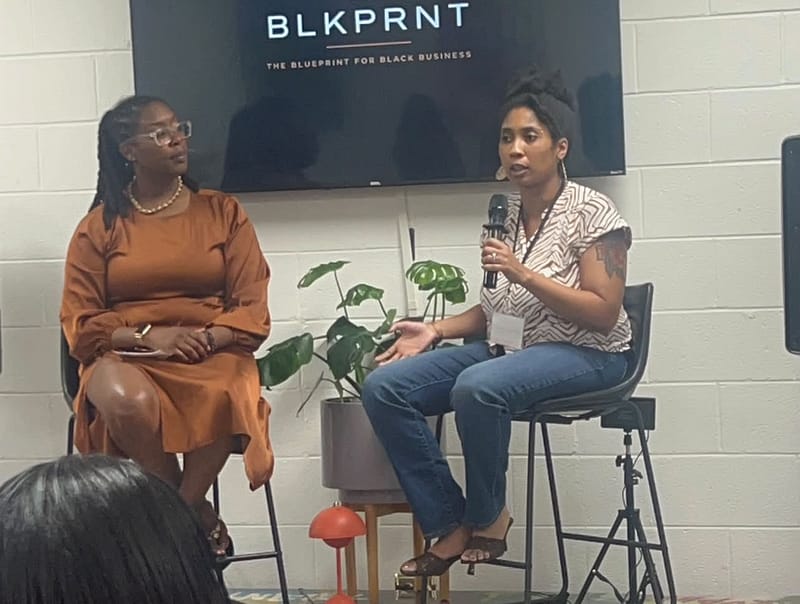 Speaker with a microphone during a panel at The Art of Business, Black Entrepreneur Week 2026 in Raleigh, hosted by The BLKPRNT